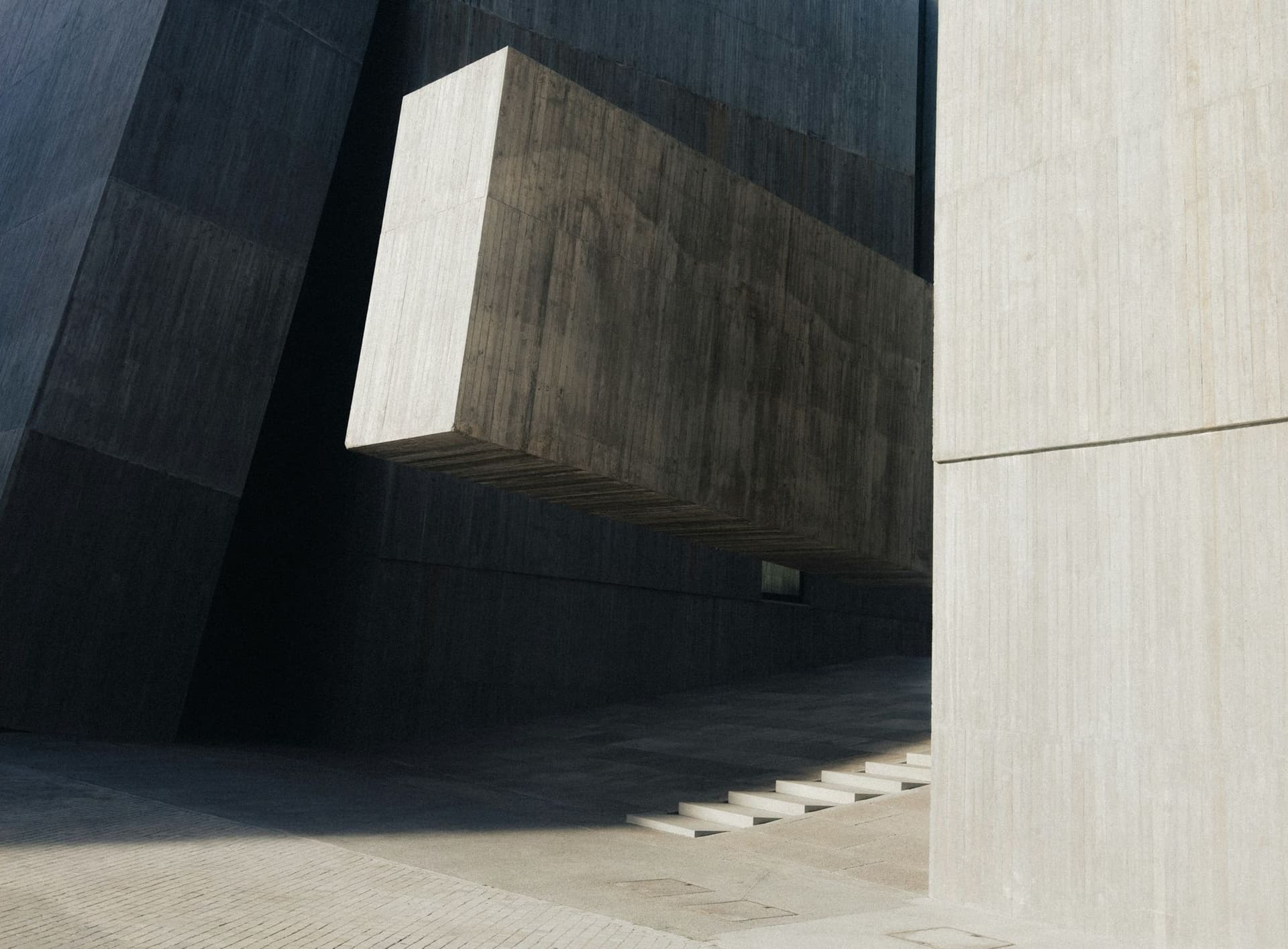 Moderní betonová architektura s vykonzolovaným hranolem a schodištěm ve stínu